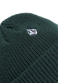 Knitted dark green beanie hat featuring a small white logo patch. The texture is ribbed, providing a soft and snug fit.