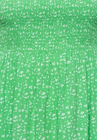 Vestido verde con corsé fruncido y falda acampanada, con un patrón floral blanco en toda la prenda sobre una tela texturizada.