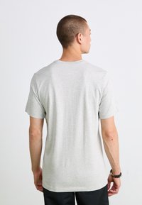 Grå t-shirt lavet af bomuld, med en rund halsudskæring og korte ærmer. Bagfra ses en afslappet pasform med minimal detaljer.