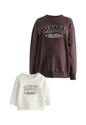Dunkelbrauner, übergroßer Sweatshirt mit "MAMA CLUB" in weißem Text über einem weißen, verkürzten Sweatshirt mit "MINI CLUB" in grauem Text.