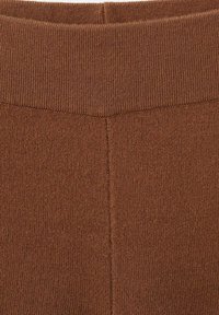 Gros plan sur un tissu marron tricoté avec une ceinture côtelée et une couture verticale au centre.