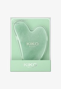 Hjerteformet grønn jade gua sha-verktøy i gjennomsiktig emballasje, merket "GLOW SCULPT" med sølvdetaljer og bakgrunn i mintgrønn.