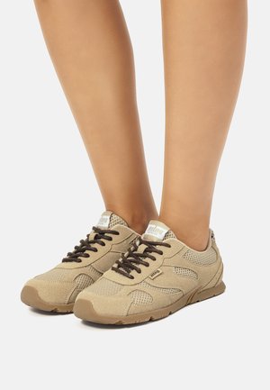 Zapatillas beige con paneles de malla, cordones marrones y suela de goma. Presenta una marca en la lengüeta y en el lado. Diseño ligero y transpirable.