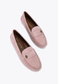 Różowe zamszowe mokasyny z okrągłym noskiem, dekoracyjnym haftem i złotą emblematyczną ozdobą na cholewce. Gładka, fakturowana powierzchnia.