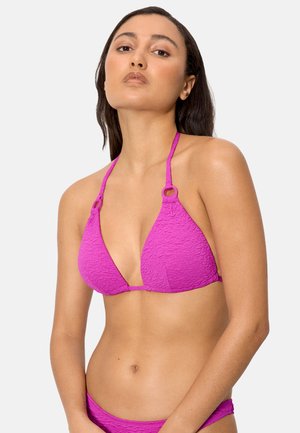 Mujer con cabello largo y oscuro, vistiendo un top de bikini halter texturizado y brillante en color rosa, con la parte inferior a juego, sobre un fondo liso.
