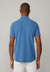 Blaue Poloshirt aus strukturiertem Stoff, mit kurzen Ärmeln und klassischem Kragen. Das Design verfügt über einen geraden Saum und subtile Nähte.