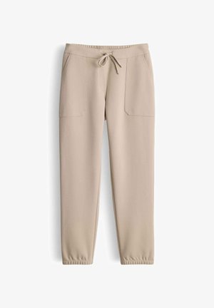 Beige joggers gemaakt van zachte stof, met een elastische tailleband met trekkoord, zijzakken en taps toelopende boorden bij de enkels.