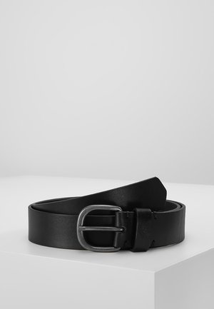 Black leather belt coiled with matte silver rectangular buckle, placed on white pedestal against plain light gray background.