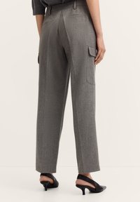 Graue maßgeschneiderte Hosen aus einem strukturierten Stoff, mit einem geraden Bein-Design und seitlichen Cargo-Taschen, kombiniert mit schwarzen High Heels.