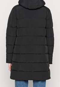 Černá puffová bunda s kapucí, verticalně prošívanými částmi, volným střihem a hladkým, mírně lesklým povrchem.