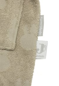 Zacht beige stof met gemêleerde patronen, met labels waarop "Jollein" en "Miffy" staan. Ontworpen voor comfort en tastbare ervaring.