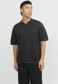 Polo en denim noir sans col et à manches courtes. Présente une finition texturée et des coutures contrastées au niveau des ourlets.