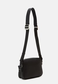 Borsa a tracolla nera in pelle con tracolla regolabile in nylon, hardware in argento, forma rettangolare e chiusura a zip. Design minimalista senza motivi.