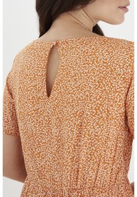 Pomarańczowa sukienka w wzór, z krótkimi rękawami, dekoltem z otworem i zapięciem na guzik z tyłu oraz marszczonym paskiem w talii.