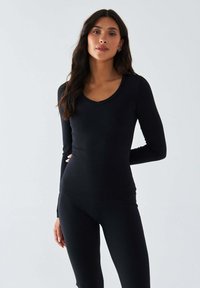 Schwarzes langärmliges Oberteil mit V-Ausschnitt, aus glattem, dehnbarem Stoff gefertigt. Eng anliegende Silhouette betont die Körperform; keine sichtbaren Muster oder Verzierungen.