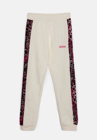 Cremefarvede sweatpants med pink leopardmønstrede sidestriber. Har elastisk talje og manchetter. "GUESS" logo i pink på fronten.