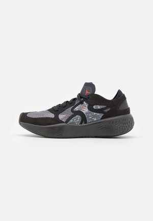 Baskets de sport noires et grises avec motif en grille, semelle épaisse, lacets noirs et logo rouge sur le côté et la languette, vues de côté.