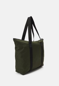 Grön tygkasse med dragkedja, med svarta remmar i textil, enkel form och slät textur. Inga ytterligare utsmyckningar.