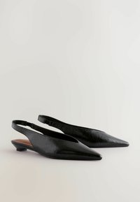 Svarta slingback-skor med en spetsig tådesign, med en strukturerad yta och en liten blockklack. Inuti har de en brun accent.