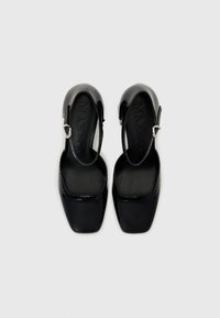 Schwarze Lackleder Slingback-Schuhe mit quadratischer Zehenpartie und mittelhohem Blockabsatz. Mit einer kleinen silbernen Schnalle am Knöchelriemen.