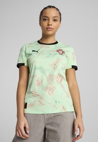 T-shirt de sport vert menthe avec des accents noirs, présentant un motif texturé et un logo sur la poitrine. Manches courtes et encolure ronde.