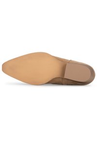 Zapato de tacón alto de ante beig con punta afilada, suela lisa y parte superior texturizada. Presenta un tacón moderadamente curvado.