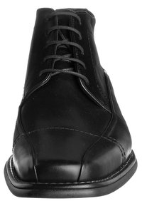 Scarpa in pelle nera con punta arrotondata, design con lacci, dettagli di cucitura sottili e una superficie liscia sulla parte superiore. Suola in gomma.