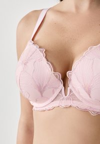 Roze kanten bh met ingewikkelde bloemenborduursels, gegolfde randen en verstelbare bandjes. Zachte netbeker zorgt voor subtiele vorming.
