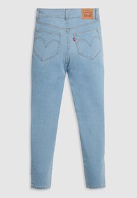 Jeans de mezclilla azul claro con cintura alta, que presentan dos bolsillos traseros, un patrón de costura curvado distintivo y una etiqueta de marca de cuero marrón.