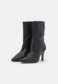 Botines de cuero negro hasta el tobillo con puntera afilada, texturizados con un patrón perforado a cuadros y con un tacón de altura media.