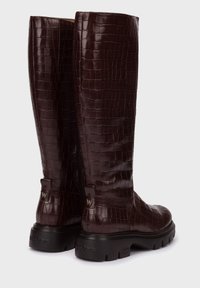 Botas de cuero marrón con estampado de cocodrilo hasta la rodilla, con un acabado texturizado, un cierre lateral y una suela negra gruesa que presenta el logo de la marca.