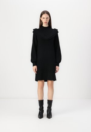 Schwarzes gestricktes Kleid mit einem schwingenden, gerippten Kragen und langen Ärmeln. Das Kleid hat einen geraden Schnitt und endet direkt oberhalb der Knie.