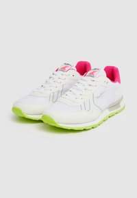 Witte sneakers met een gestructureerde afwerking, roze accenten op de tong en een neon groene buitenzool. Voorzien van veters en merkvermelding op de zijkant.