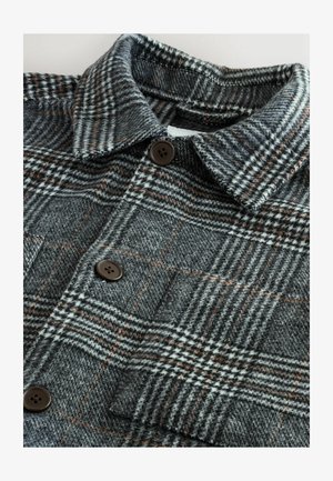 Chaqueta de cuadros en gris y negro, confeccionada con una tela texturada, que presenta un cuello con solapa, dos cierres de botón marrón y un bolsillo en el pecho.