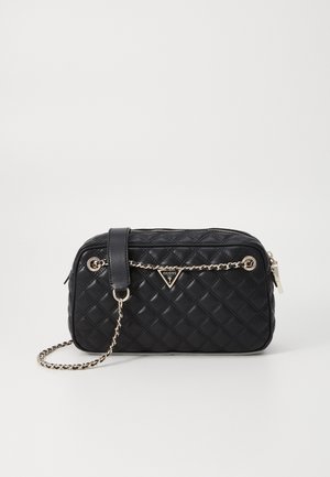 Sac à main rectangulaire matelassé noir avec bandoulière chaîne dorée et logo Guess sur le devant, sur fond clair uni.