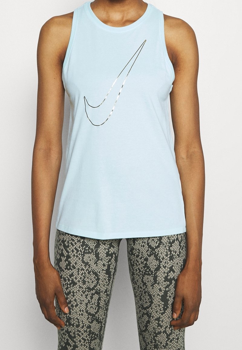 Camiseta sin mangas de color azul claro en tejido suave, con un logotipo metálico de Nike. Combinada con leggings ajustados en un estampado de serpiente.