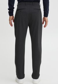 Charcoal gray tailored trousers with two back pockets and button closures, featuring a straight leg design and material giving a smooth texture.