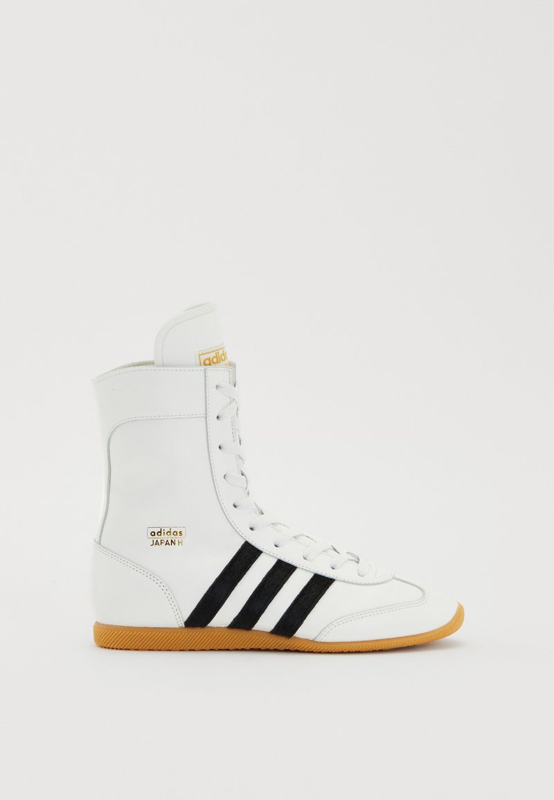 Hochschnittige weiße Ledersneaker mit schwarzen Streifen, orangefarbener Markenkennzeichnung und strukturiertem Gummisohle. Verfügt über eine Schnürung vorne und einen gepolsterten Kragen.