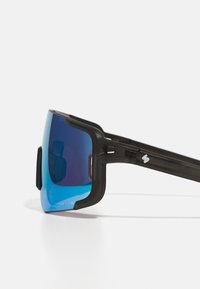 Sonnenbrille mit schwarzem Kunststoffrahmen und großen blauen verspiegelten Gläsern. Sie verfügt über ein elegantes Design mit auffälligen seitlichen Akzenten.