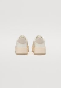 Hvite lær sneakers med teksturert bakpanel, lysfarget plattformsåle og runde lisser; glatt overflate og minimalistisk design.