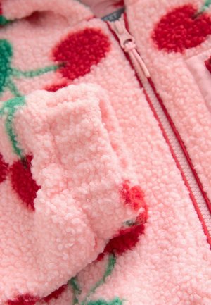 Jachetă din fleece roz, cu fermoar, având modele cu cireșe roșii și tulpini verzi. Textura este moale și pufoasă, cu un detaliu de fermoar care se poate închide.
