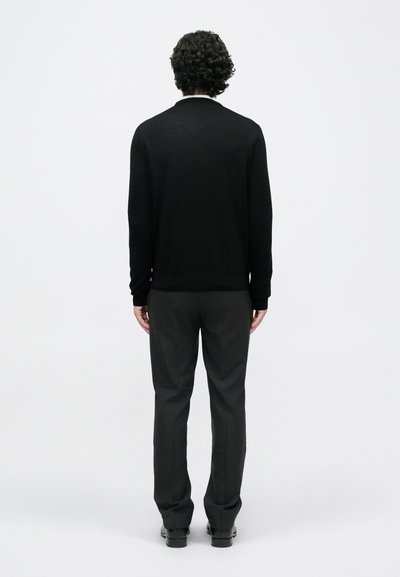 Pull en tricot noir à manches longues, associé à un pantalon gris bien ajusté. Texture lisse et douce ; design minimaliste, sans motifs visibles.