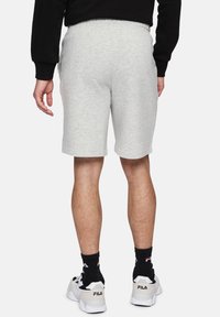 Lichtgrijze katoenen shorts met een elastische tailleband, zijzakken en een relaxte pasvorm, gecombineerd met witte en zwarte sneakers.