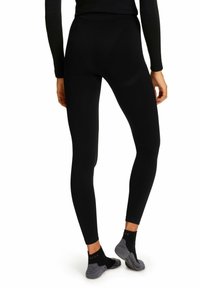 Schwarze Leggings mit einer enganliegenden Passform, glatter Textur, hohem Bund und verstärkten Nähten, kombiniert mit kontrastierenden grauen Knöchelsocken.