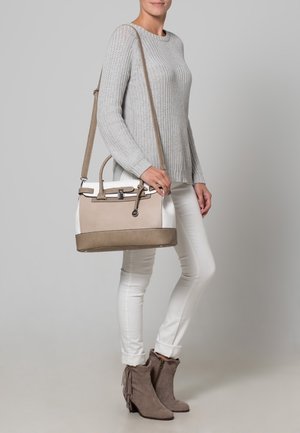 Sac à main beige et blanc au design structuré, matériaux lisses et texturés, agrémenté d'une bandoulière amovible et de ferrures argentées.