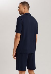 Marineblauw twee-delig outfit gemaakt van zachte stof, bestaande uit een kortekraag shirt met korte mouwen en bijpassende shorts met een comfortabele pasvorm.