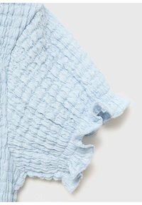 Svetle modrá strukturovaná tkanina s krčeným designem. Volánkový detail na rukávu. Hladká, jemná textura s jemným vzorem.