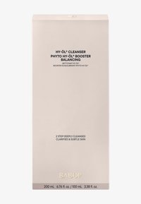 Emballage du nettoyant Babor HY-ÖL, rectangulaire, beige clair avec finition mate. Texte noir détaillant le nom du produit et les instructions, logo doré.