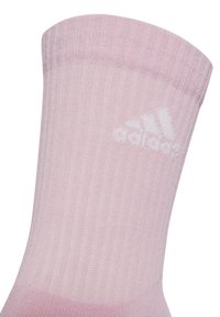 Svetloružová rebrovaná športová ponožka s hladkým povrchom, so bielym logom Adidas blízko členka.