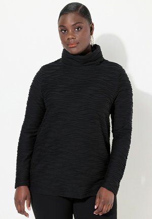Maglia nera a maniche lunghe con collo a cascata. Presenta un motivo a onde testurizzato e un materiale morbido. Modello con maniche aderenti e vestibilità rilassata.